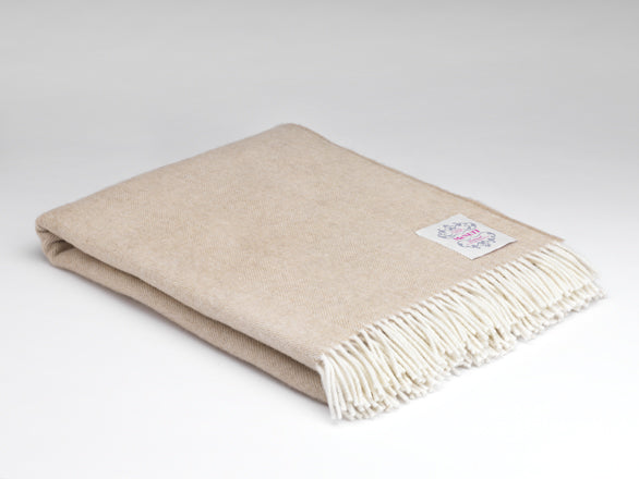 Beige blanket with white fringe on a light gray background