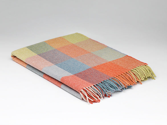 Multicolored checkered blanket with frayed edges on a light gray background
